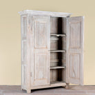 Side angle image with open doors of a Kaiden reclaimed teak wood wardrobe with hand-carved Indian details, double doors, and vintage whitewashed finish.