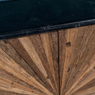 Close up of the marble top of a reclaimed wood sideboard with sunburst carved doors, sliding black marble top, and rustic finish, ideal for rustic interior design.