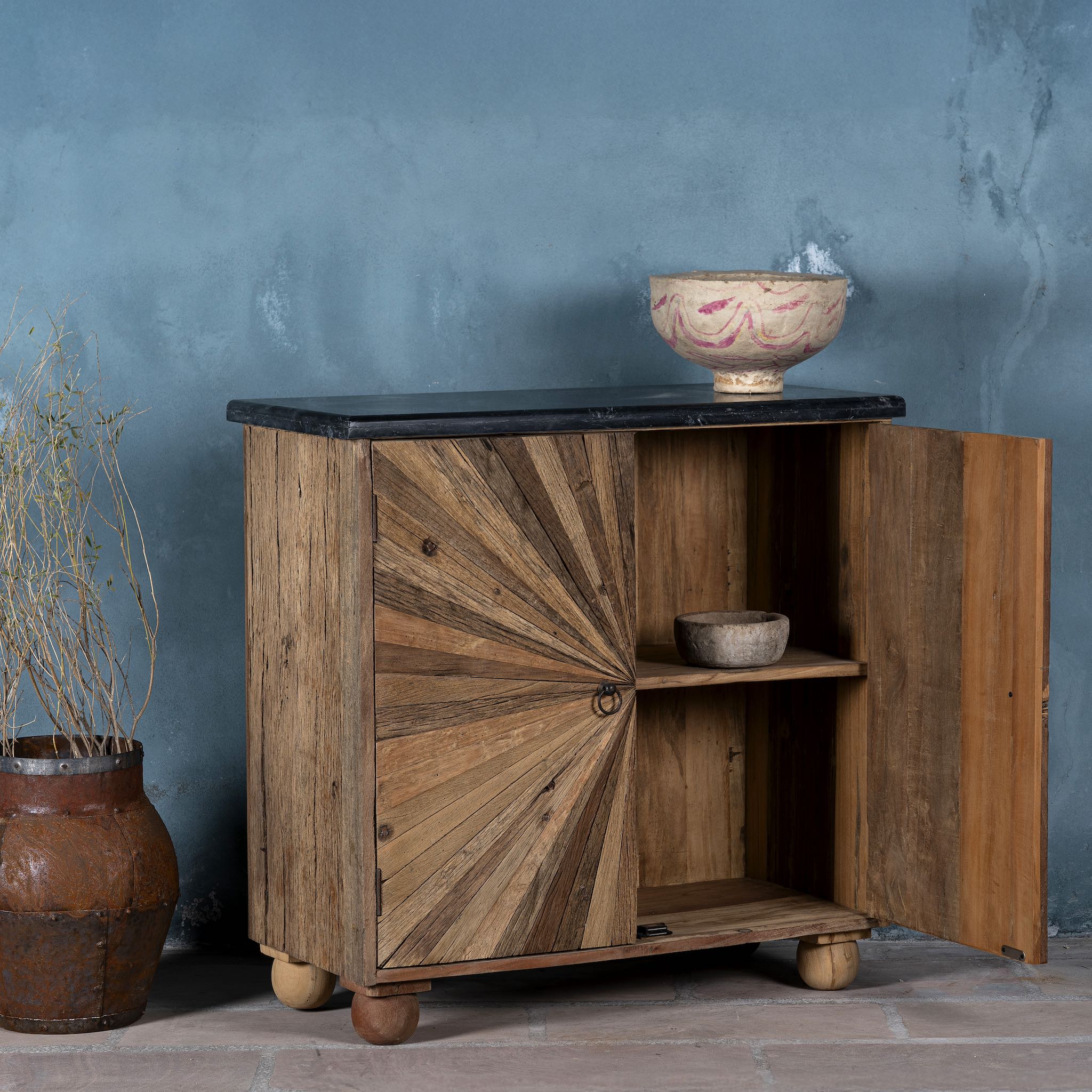 Open door image of a  reclaimed wood sideboard with sunburst carved doors, sliding black marble top, and rustic finish, ideal for rustic interior design.