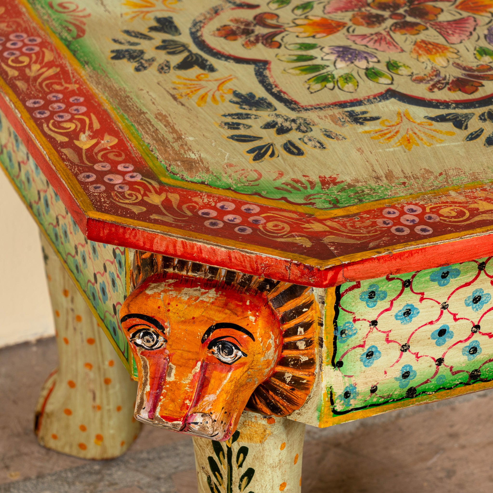 Close up image of a Kaliana hand-painted reclaimed wood coffee table with sculpted tiger heads and colourful floral design 80cm