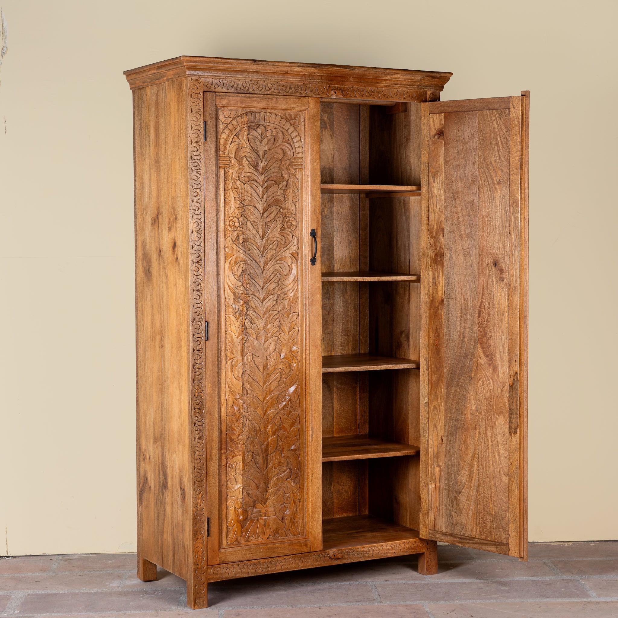 Side angle image with open door of a Kalki hand carved mango wood wardrobe with botanical carved doors, removable shelves and hanging rail, 110x56x190cm