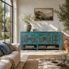 Lifestyle image of a Kalpana reclaimed wood console table with blue distressed finish, carved doors, three drawers, enclosed storage and open lower shelf.