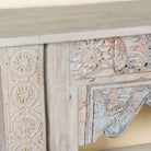 Close up image of a Karam reclaimed teak console table with hand-carved Indian details, lower shelf, and vintage whitewashed finish.