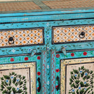 Close up image of a Kaveh hand painted reclaimed wood sideboard in boho style with three doors, three drawers, floral details, and distressed turquoise finish.