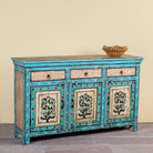 Side angle image of a Kaveh hand painted reclaimed wood sideboard in boho style with three doors, three drawers, floral details, and distressed turquoise finish.