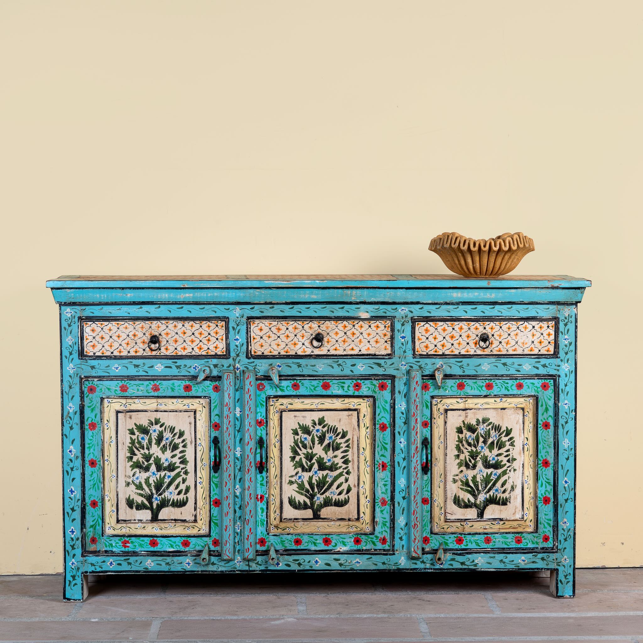 Kaveh hand painted reclaimed wood sideboard in boho style with three doors, three drawers, floral details, and distressed turquoise finish.