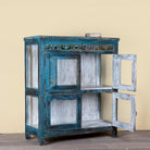 Side angle image with open door of a Kavish vintage blue reclaimed teak wood wardrobe with peacock reverse glass paintings and distressed Indian finish.