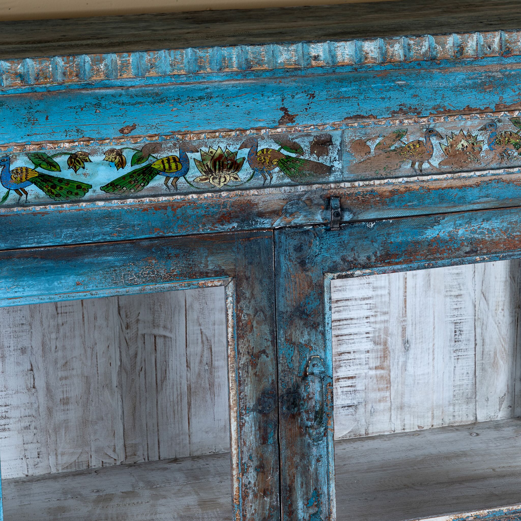 Close up image of a Kavish vintage blue reclaimed teak wood wardrobe with peacock reverse glass paintings and distressed Indian finish.