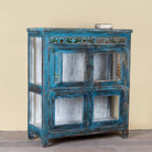 Side angle image of a Kavish vintage blue reclaimed teak wood wardrobe with peacock reverse glass paintings and distressed Indian finish.