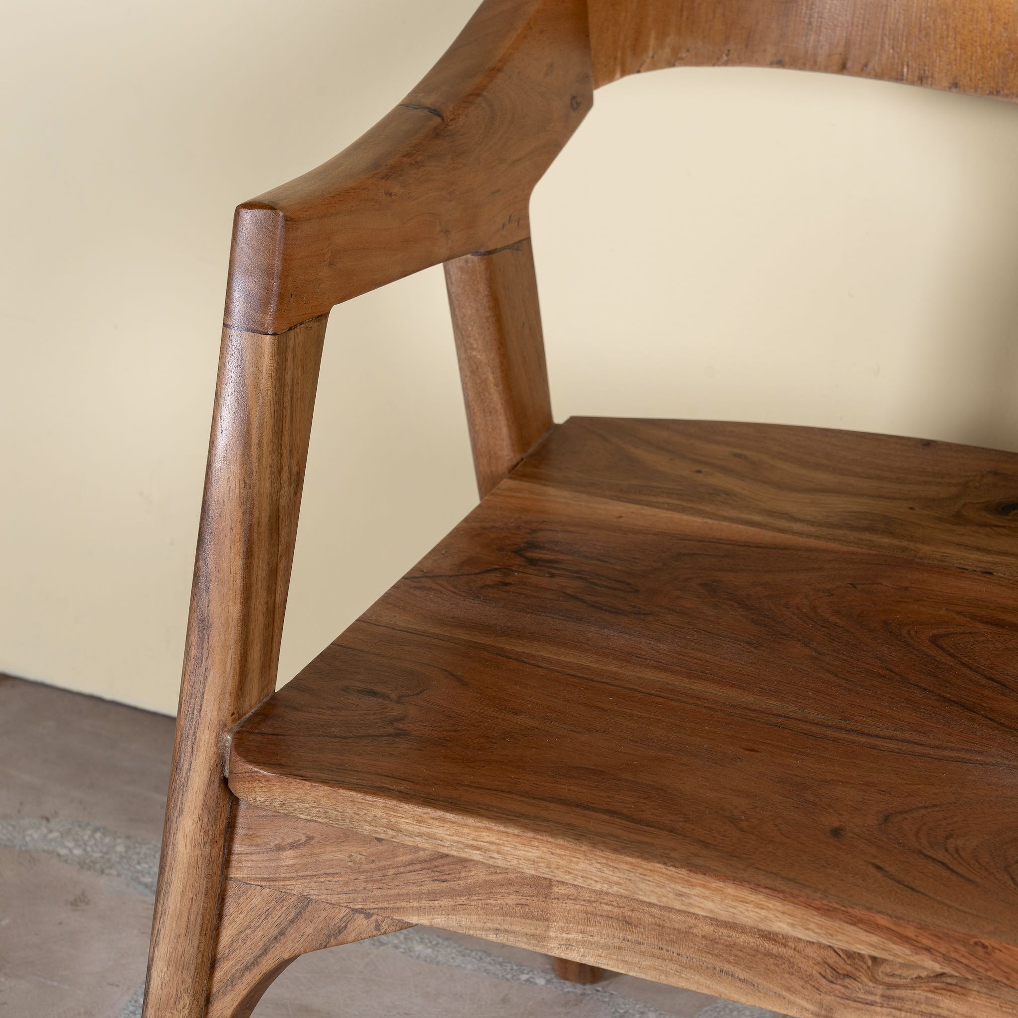 Close up image of a wooden armchair made of solid acacia wood with curved backrest and armrests; acacia wood chair, 60 × 50 × 90 cm.