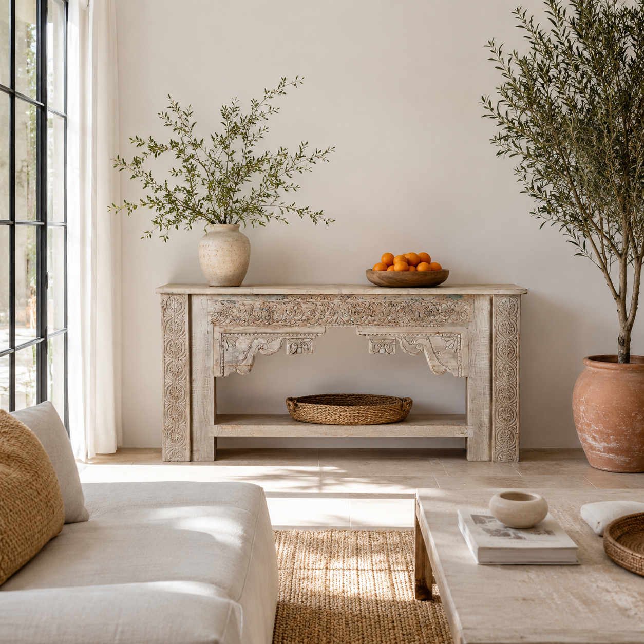 Lifestyle image of a Kayleb reclaimed teak console table with hand-carved Indian floral details, lower shelf, and whitewashed vintage finish.