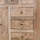 Close up view of a hand carved mango wood cupboard with 6 drawers and 1 door, iron fitted door knobs and floral carvings.