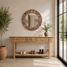 Lifestyle image of a handcrafted round mango wood mirror with patchwork reclaimed frame and distressed finish; ideal for vintage home decor, 80 × 4 cm.