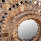 Close up image of a round mango wood mirror Kiaan with concentric carved design and mirror inlays. A piece of unique wall decor combining artisanal craftsmanship and rustic bohemian charm.