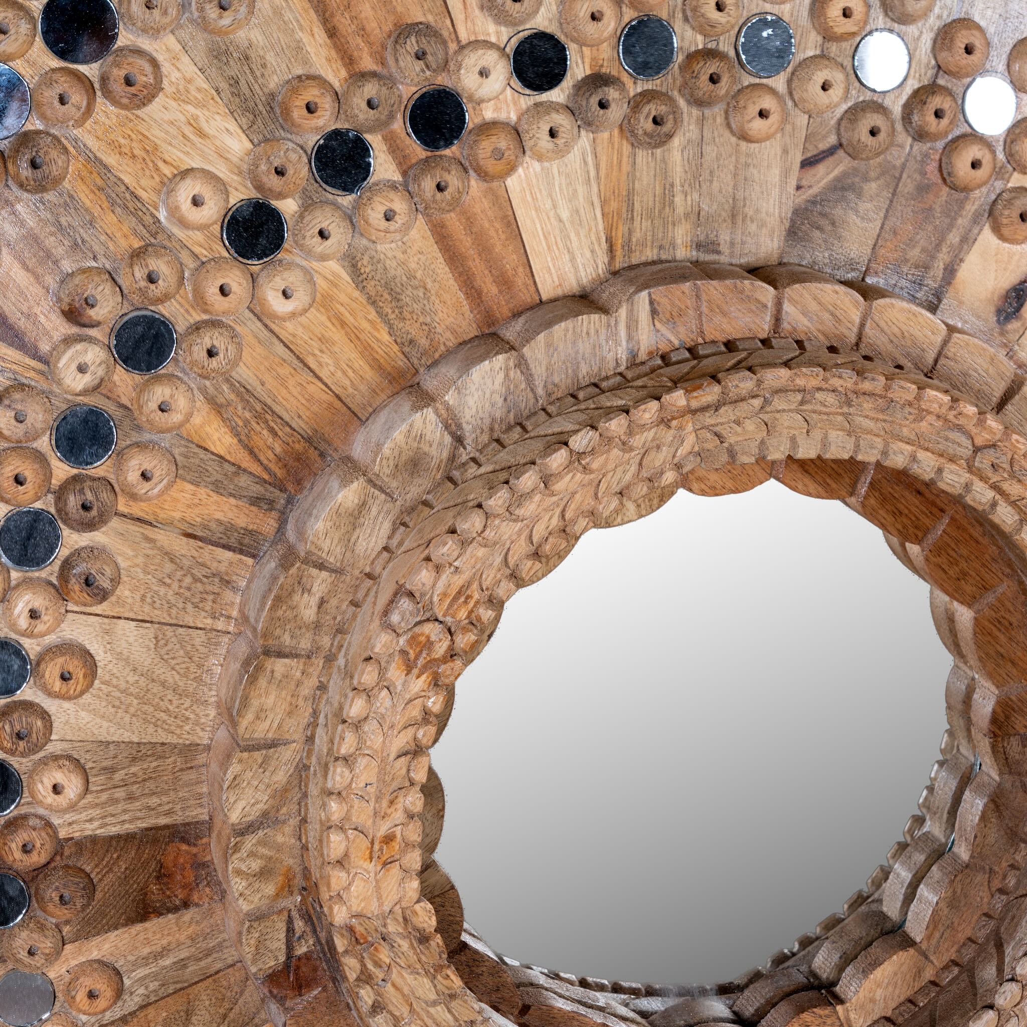 Close up image of a round mango wood mirror Kiaan with concentric carved design and mirror inlays. A piece of unique wall decor combining artisanal craftsmanship and rustic bohemian charm.