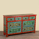 Side angle image of a Kianraj hand painted reclaimed wood chest of drawers with red frame, blue floral fronts and eight drawers 150cm