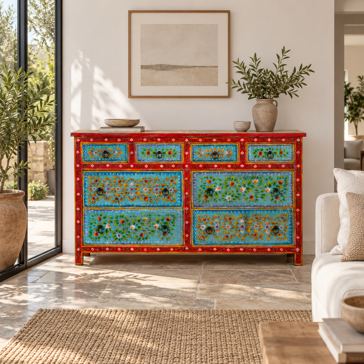 Lifestyle image of a Kianraj hand painted reclaimed wood chest of drawers with red frame, blue floral fronts and eight drawers 150cm