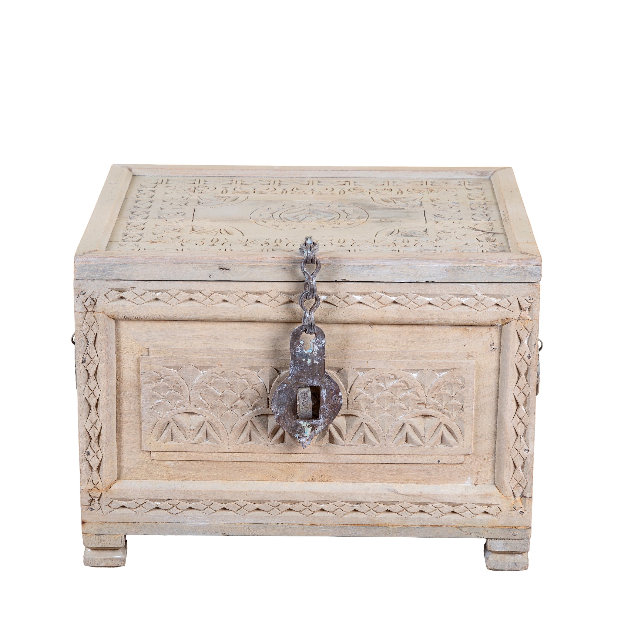 A rectangular carved wooden chest with a distressed light beige finish, featuring intricate floral engravings on the front and lid, a decorative metal latch, and small feet at the bottom, shown on a plain white background.