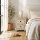 Lifestyle scene with a whitewashed nightstand made of mango wood with Mediterranean-style carved detailing and one drawer –Kirandeep bedside table by Om Home & Garden