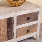Close up image of a Kishen handcrafted reclaimed wood lowboard with driftwood front detailing, carved cabinet doors, four drawers, and natural rustic boho style finish.