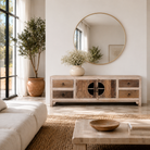 Lifestyle image of a Kishen handcrafted reclaimed wood lowboard with driftwood front detailing, carved cabinet doors, four drawers, and natural rustic boho style finish.