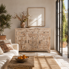 Lifestyle image of a image of a hand-carved mango wood cabinet with three drawers and vintage distressed finish; ideal for mango wood furniture lovers and vintage home decor, 150 × 110 × 40 cm.