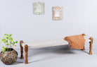Side angle image of a low mango wood bench with handwoven cotton seat and hand-carved recycled wood frame; 180 × 45 × 20 cm.