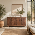 Lifestyle imageof a sideboard with modern appeal made of acacia wood with brass fitted doorknobs and 4 doors.