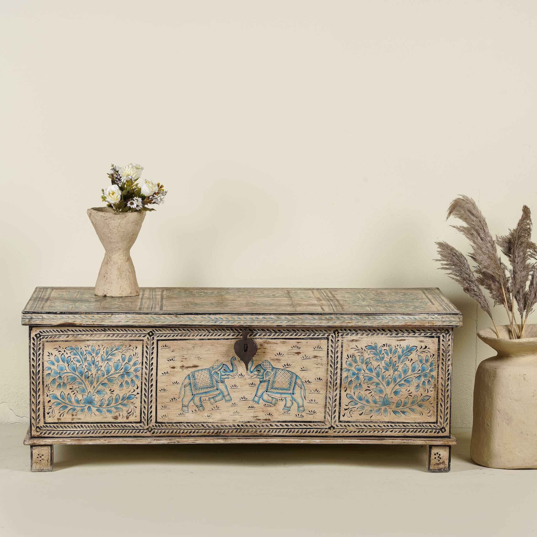 Large hand-painted chest made from old reclaimed wood, featuring intricate blue designs of elephants and floral motifs on a distressed beige background, with a central latch and a rustic vintage finish.
