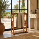 Lifestyle image of a Kundara handcrafted reclaimed teak wood towel rack with sculptural wave-shaped design, hand-carved details, natural wood grain, and rustic bathroom styling, 100cm.