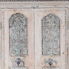 Close up image of a Kyra antique reclaimed teak wood wardrobe with intricate Indian hand carvings, double doors, and vintage distressed finish.
