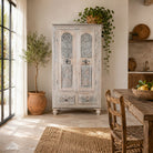 Lifestyle image of a Kyra antique reclaimed teak wood wardrobe with intricate Indian hand carvings, double doors, and vintage distressed finish.