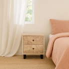 Lifestyle imagination of a pair of mango wood nightstands with hand-carved sandblasted finish and black iron stand; artisanal bedroom furniture, 51 × 41 × 59 cm.