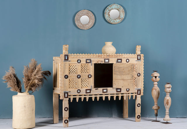 Side angle image with open door of an antique Indian treasure chest in solid teak with hand-carved detailing and sandblasted finish. A vintage home accessory ideal for Indian decor, 122 × 96 × 40 cm.