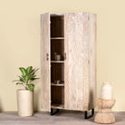 Side angle image with open door of a mango wood wardrobe with sandblasted finish and iron stand; artisanal bedroom furniture, 90 × 46 × 183 cm.