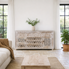 Lifestyle image of a hand-carved wooden sideboard made from solid mango wood with drawers and compartments; unique furniture piece in Mediterranean style, 180 × 100 × 40 cm.
