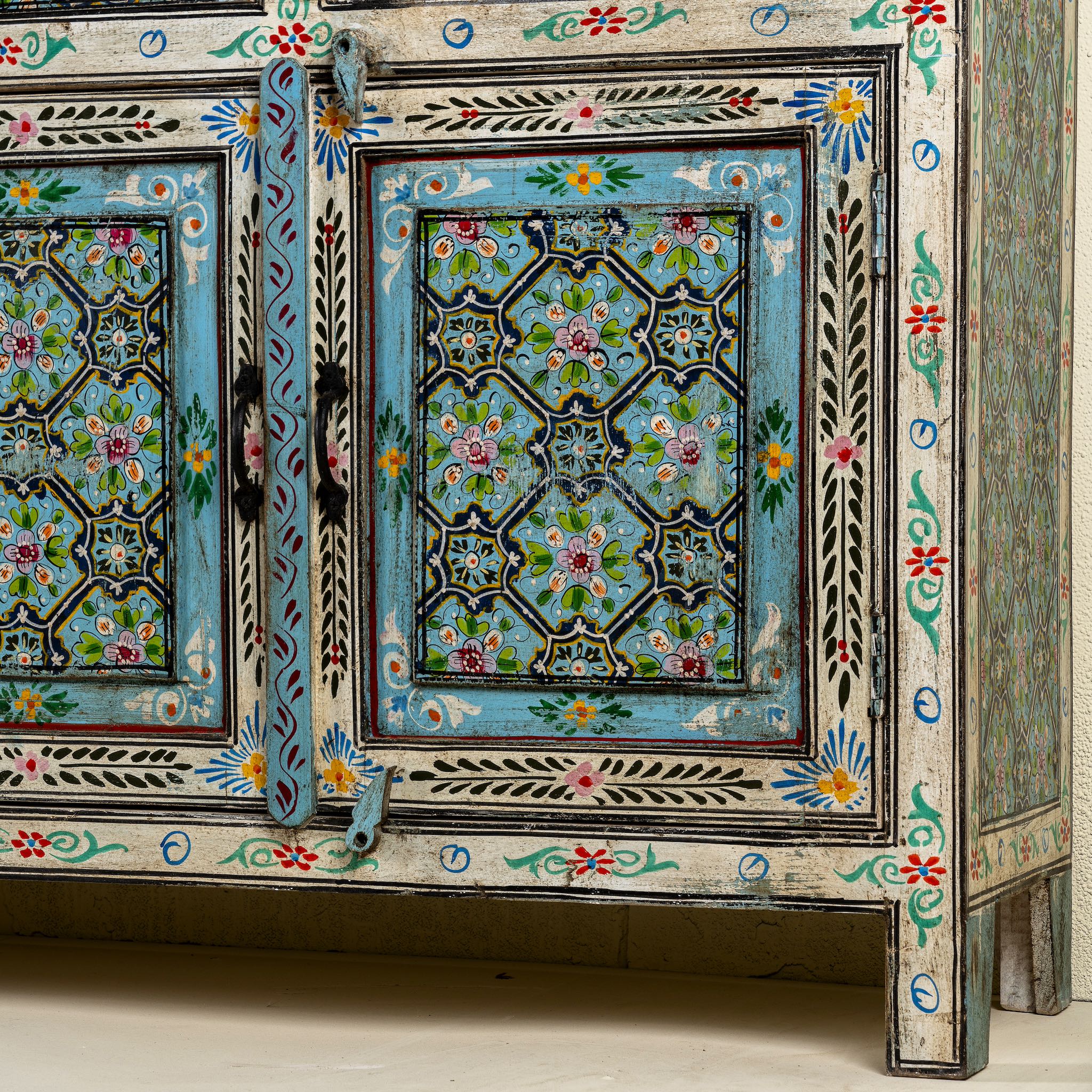 Close up image of the leg part of a hand painted furniture sideboard made from reclaimed teak wood with floral motifs, artisanal furniture in bohemian Mediterranean style, 180 × 40 × 90 cm.