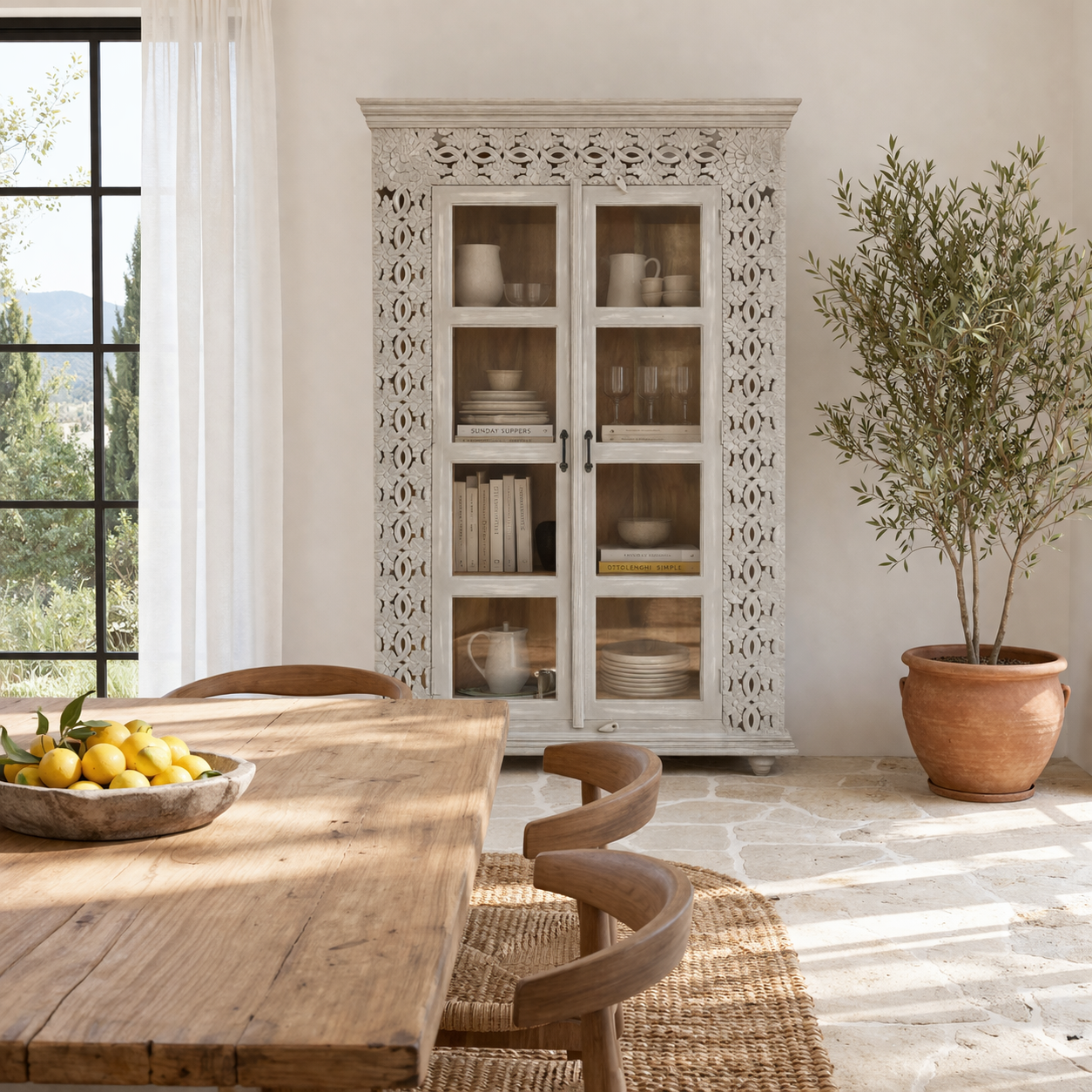 Lifestyle image of a handcrafted mango wood cabinet with glass-panelled doors and internal storage – carved wood furniture made from sustainable mango wood with unique natural grain.
