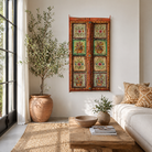 Lifestyle image of a hand-painted antique teak wood Indian door with floral motifs, rustic orange frame, reclaimed wood vintage wall panels for bohemian and vintage home decor.