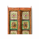 Close up image of a hand-painted antique teak wood Indian door with floral motifs, rustic orange frame, reclaimed wood vintage wall panels for bohemian and vintage home decor.