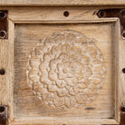Close up image of a reclaimed teak wood console table with hand-carved floral fronts and iron accents; sustainable furniture, 153 × 80 × 40 cm.