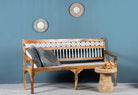 Side angle image of a hand carved mango wood bench with floral backrest and spindle accents; rustic mango wood seating, 176 × 56 × 95 cm.