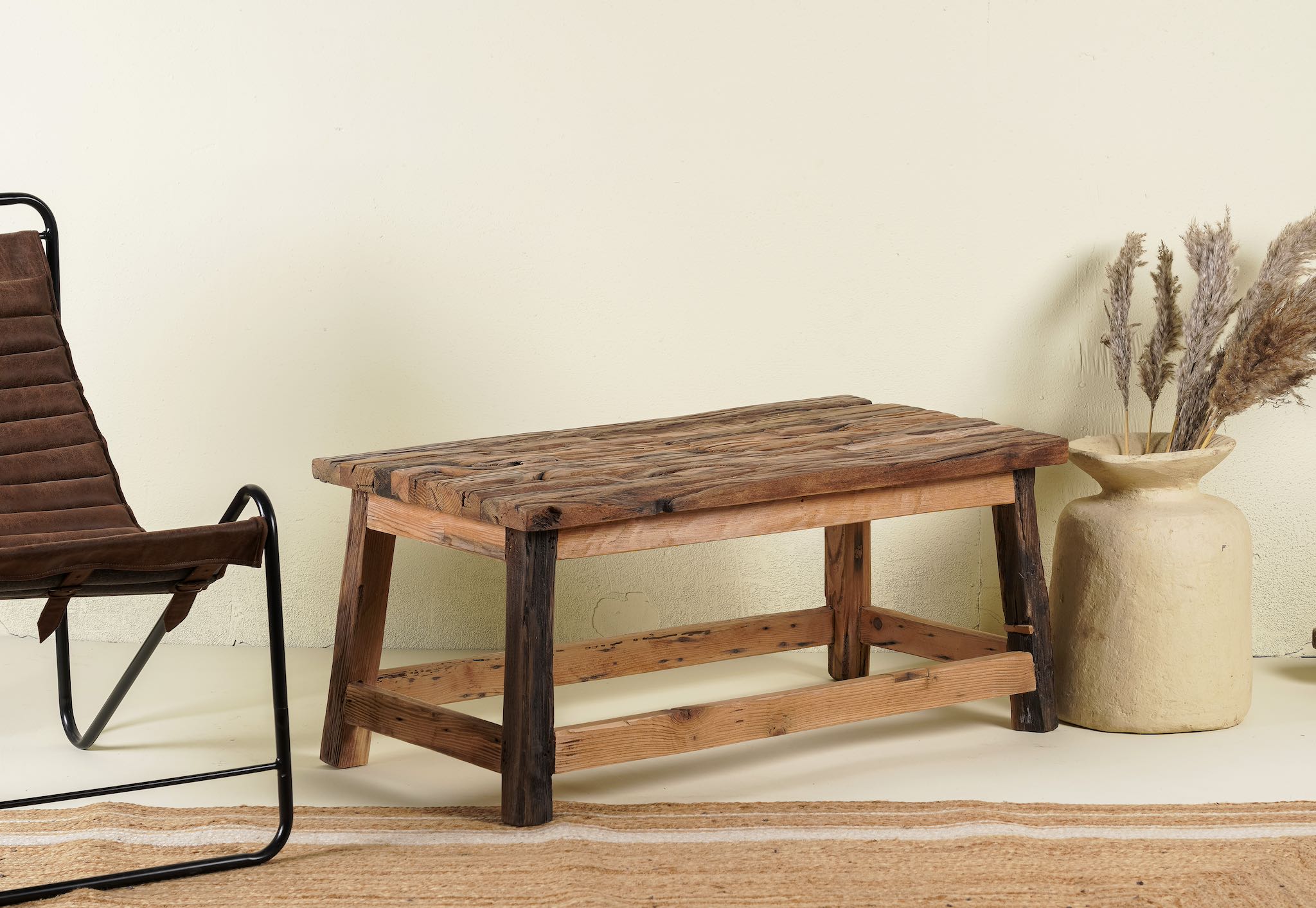 Side angle image of a Rustic driftwood coffee table made from reclaimed wood with sandblasted finish; sustainable furniture, 100 × 50 × 45 cm.