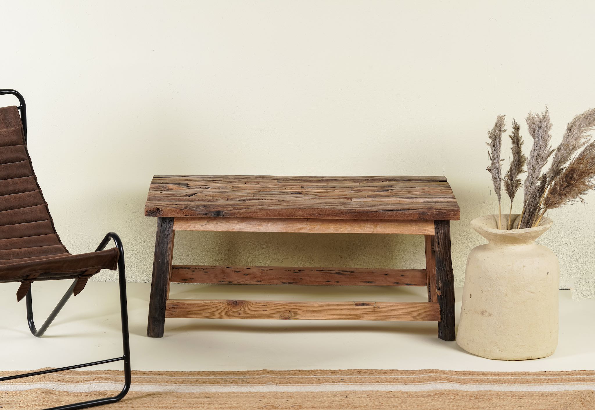 Rustic-style coffee table made from driftwood, showcasing a textured, uneven surface with natural wood tones and grain variations, supported by a sturdy, simple wooden frame, styled in a cozy minimal setting with neutral decor.
