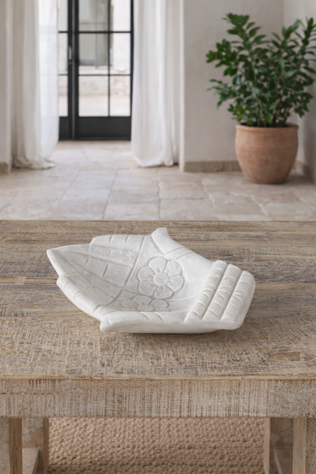 Lifestyle imagination of a white marble decorative bowl shaped like cupped hands with floral carving – hand-carved Indian marble accessory.