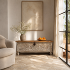 Lifestyle Image of a Hand-carved mango wood chest box with floral motifs, whitewashed finish, and iron handles – vintage home accessory for rustic and elegant interiors.
