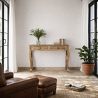 Lifestyle image of a desk made of natural mango wood with 2 drawers and carved legs.