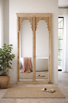Lifestyle imagination of a Antique Indian arch mirror Shalee made from a reclaimed teak wood double window with carved arches. A unique piece of rustic wall art and functional décor for bohemian or vintage-inspired interiors.