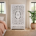 Lifestyle image of a hand-carved mango wood wardrobe with floral and geometric patterns and white-washed finish – carved wooden furniture for boho chic and Mediterranean-inspired interiors.