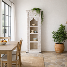 Lifestyle image of a hand carved white washed mango wood bookshelf with Mediterranean design – narrow wooden furniture piece with decorative carving and natural charm.